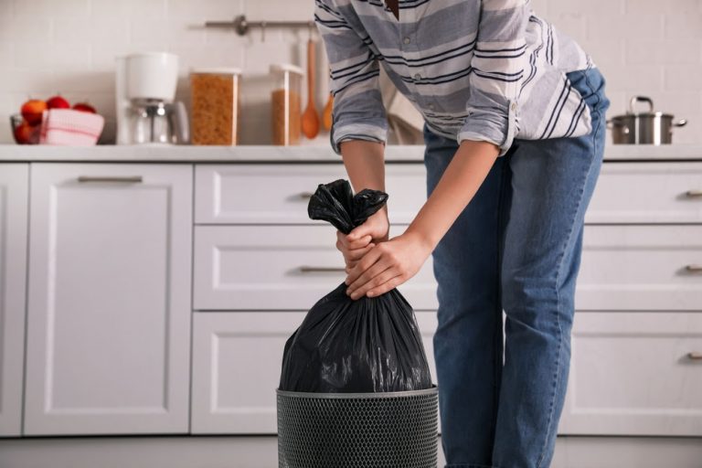 Woman taking garbage bag out of bin at home, closeup