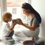 Mother and little son sitting on a windowsill with a tea