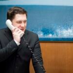 A man in a suite walking on a landline phone