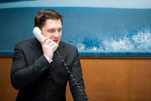 A man in a suite walking on a landline phone