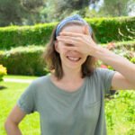 Happy woman in summer outfit covering eyes from sun