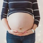 Close-up of pregnant woman's big hairy belly on bright bokeh lights background