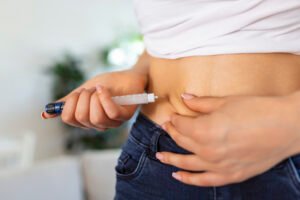 A diabetic patient using insulin pen for making an insulin injection at home. Young woman control diabetes. Diabetic lifestyle